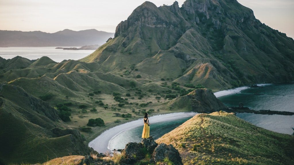 Woman standing on mountain near body of water