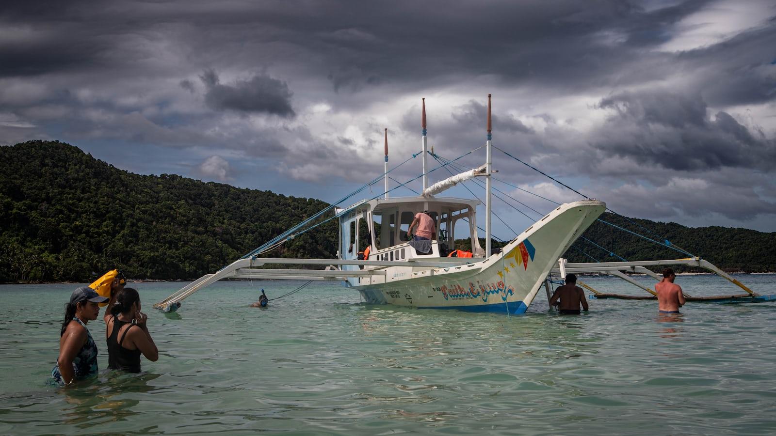 People swim near a boat in the ocean