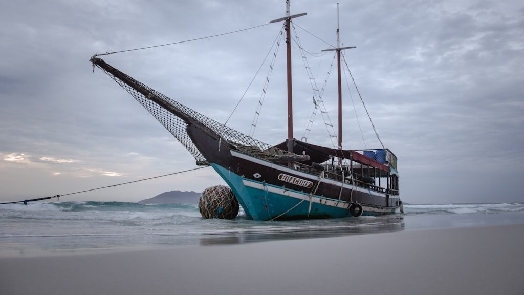 A boat sitting on top of a beach next to the ocean