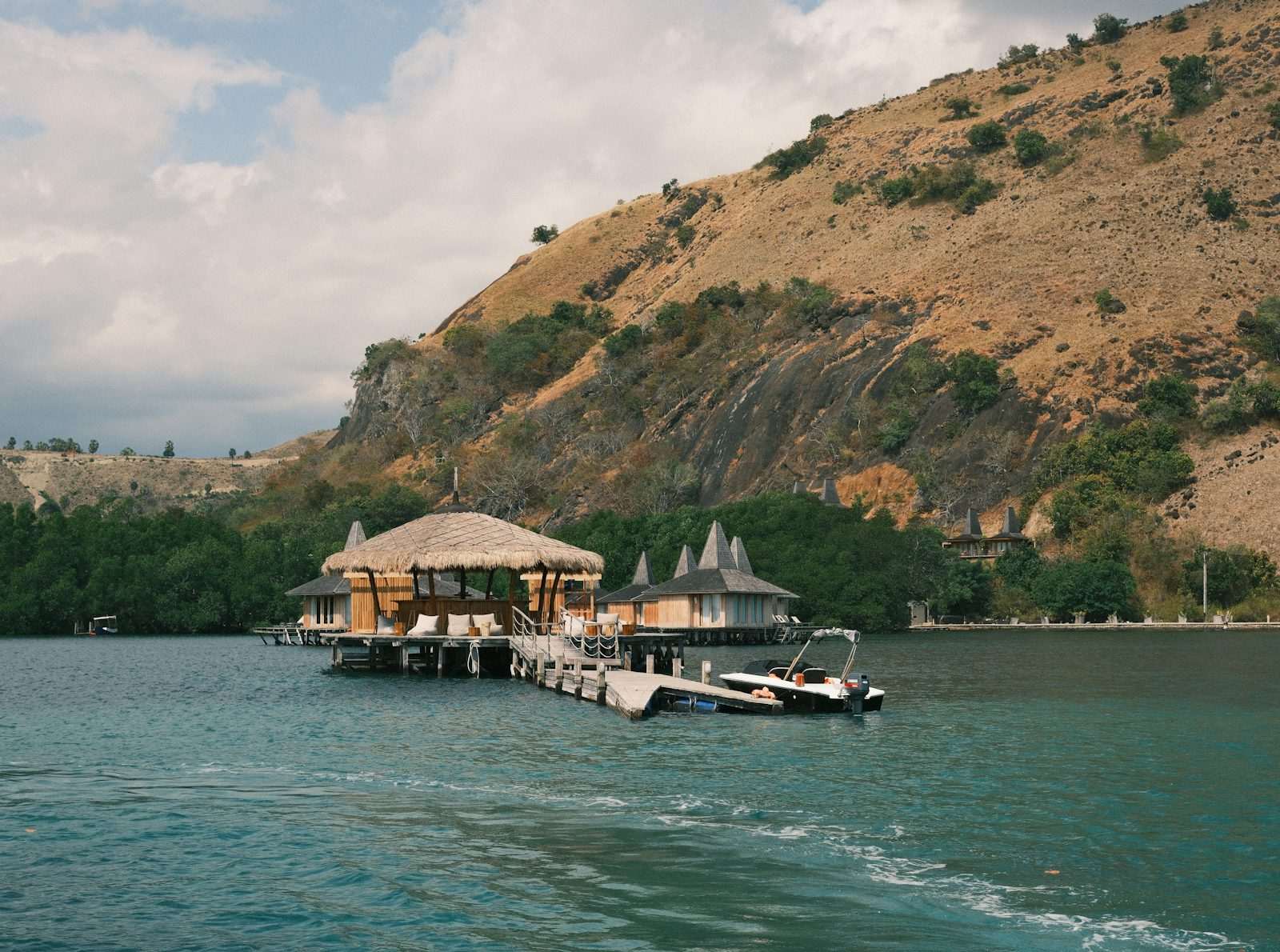 A boat traveling down a river next to a lush green hillside