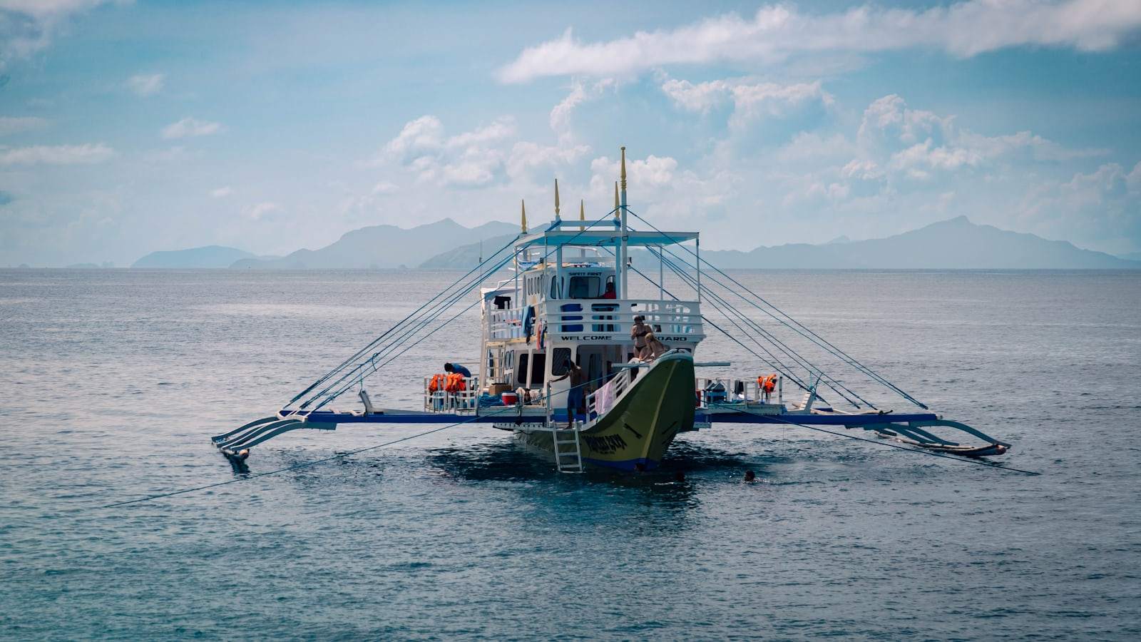 A traditional outrigger boat floats on the calm sea