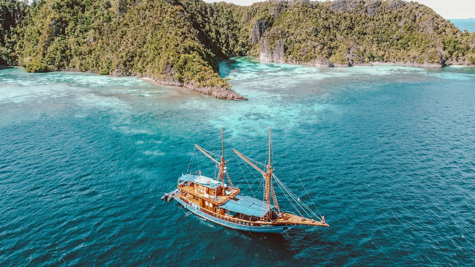 A traditional Indonesian phinisi liveaboard at anchor in a turquoise bay
