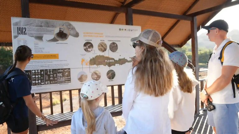 A guide explaining the park rules board to visitors