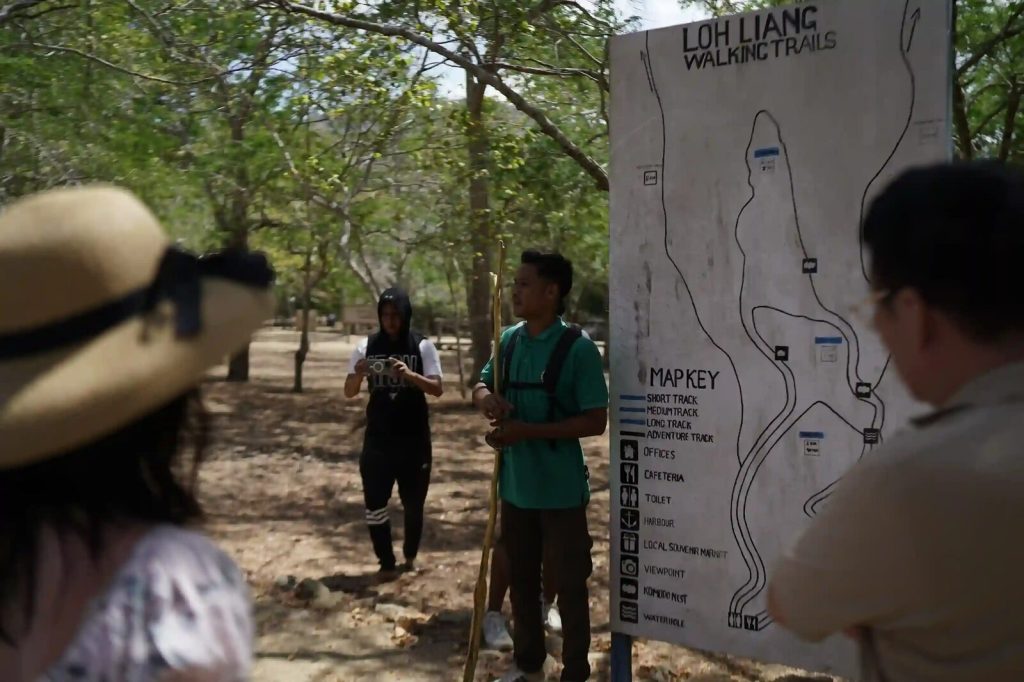 Visitors reading the Loh Liang walking-trail map board with a ranger on Komodo Island
