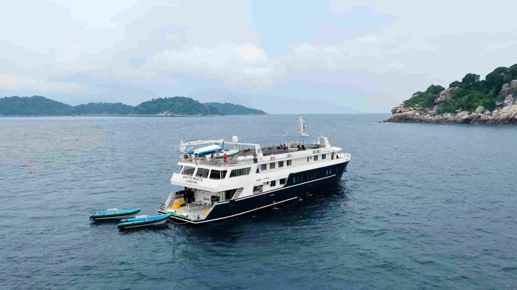 A small ship anchored off a forested island