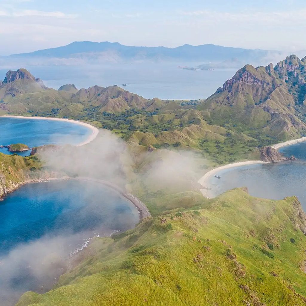 Morning mist drifting over the curved bays below the Padar Island viewpoint